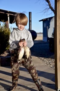 A boy holding two fish in his hands.