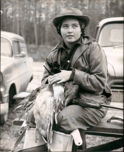 A woman sitting on the back of a truck holding a bird.