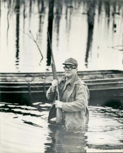A man holding a rifle in the water.