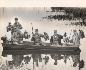 A group of men in a boat with birds.