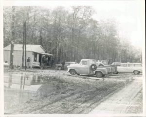 A black and white photo of cars parked in front of a house.