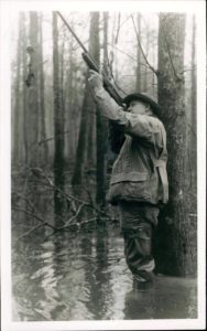 A man in the woods holding onto a tree branch.