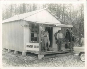 A group of men standing on the porch of a cabin.
