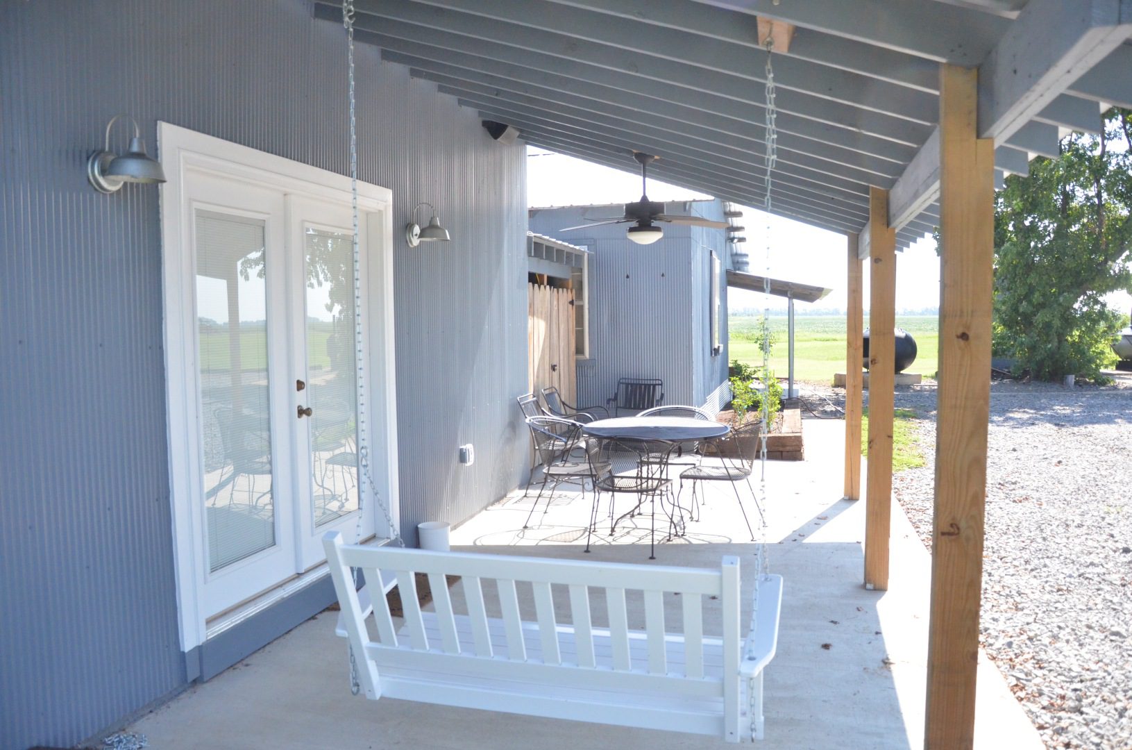 A porch swing is shown with a table and chairs.